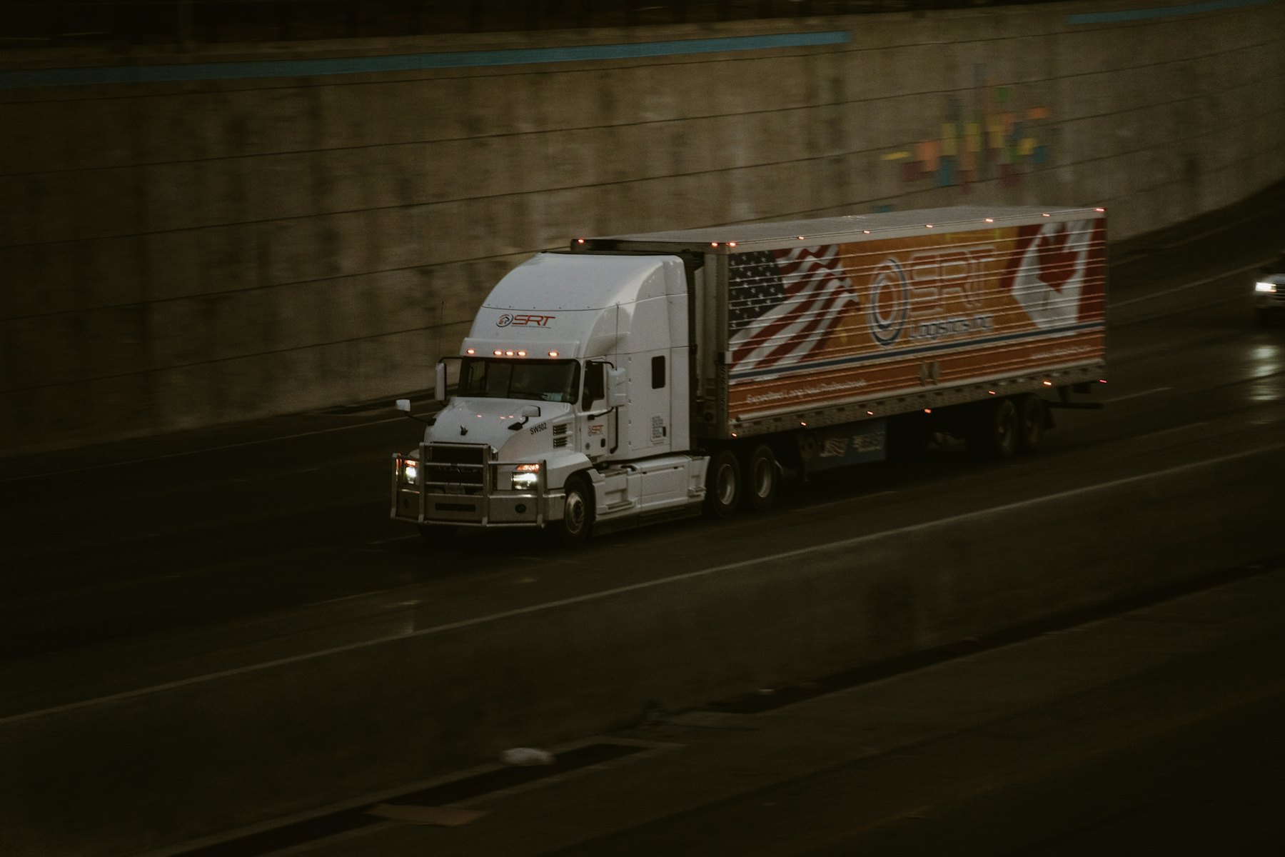 Semi truck hauling a trailer through a highway underpass